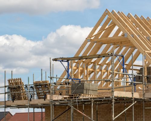 Construction industry. Timber framework of house roof trusses with scaffold. Construction industry. Timber framework of house roof trusses with scaffold on a building being built on a new housing estate.